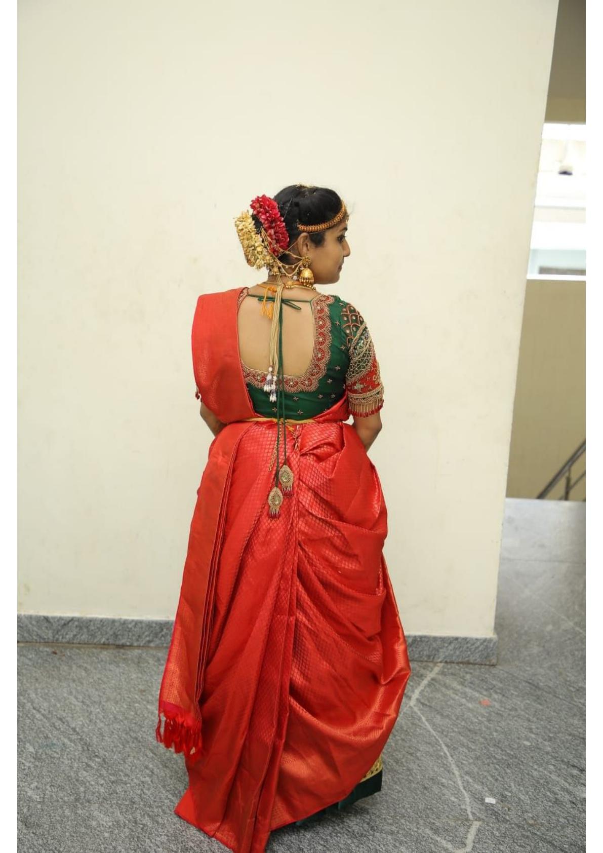 Red silk saree with green blouse and gold embroidery details