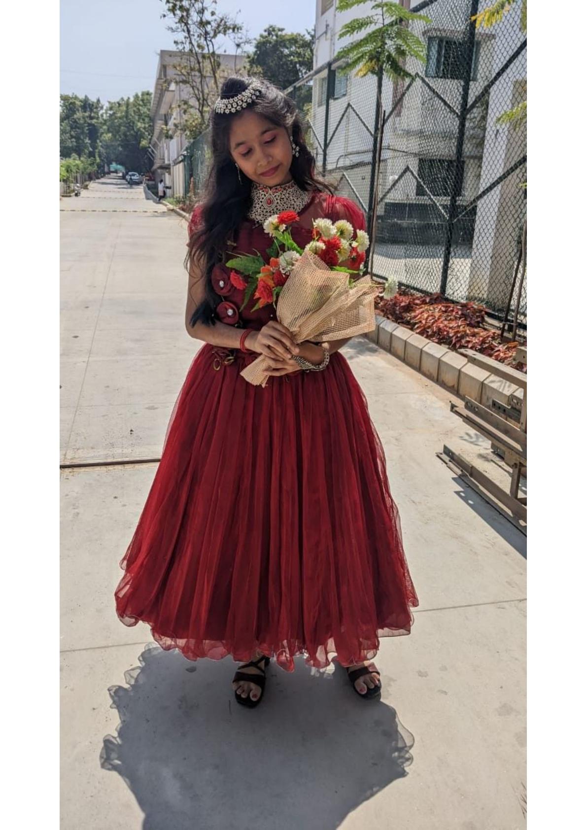 Maroon pleated gown with pearl neckpiece and floral bouquet