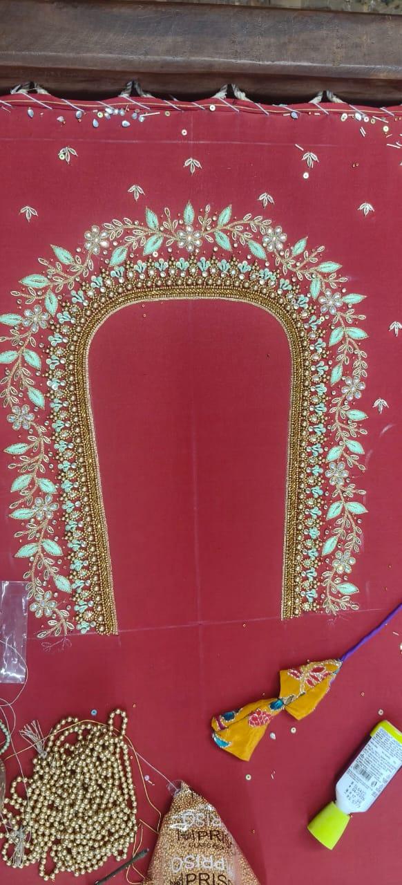Red saree blouse with ornate zari and stone embroidery, arched neckline design
