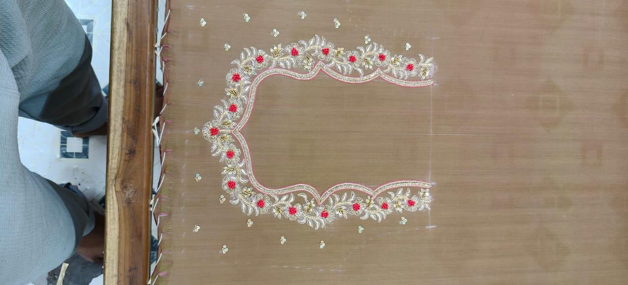 Beige fabric with red floral embroidery and gold zari work border design