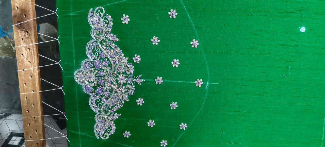 Green fabric with ornate purple embroidered motif and floral designs