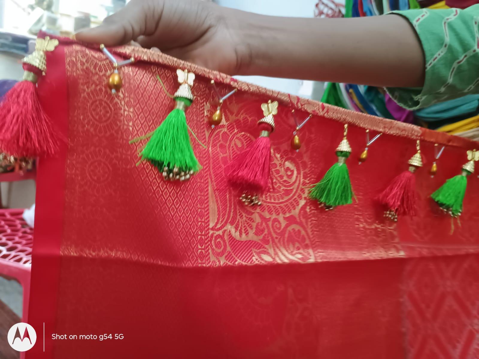 Red silk saree with gold zari work and colorful tassel embellishments