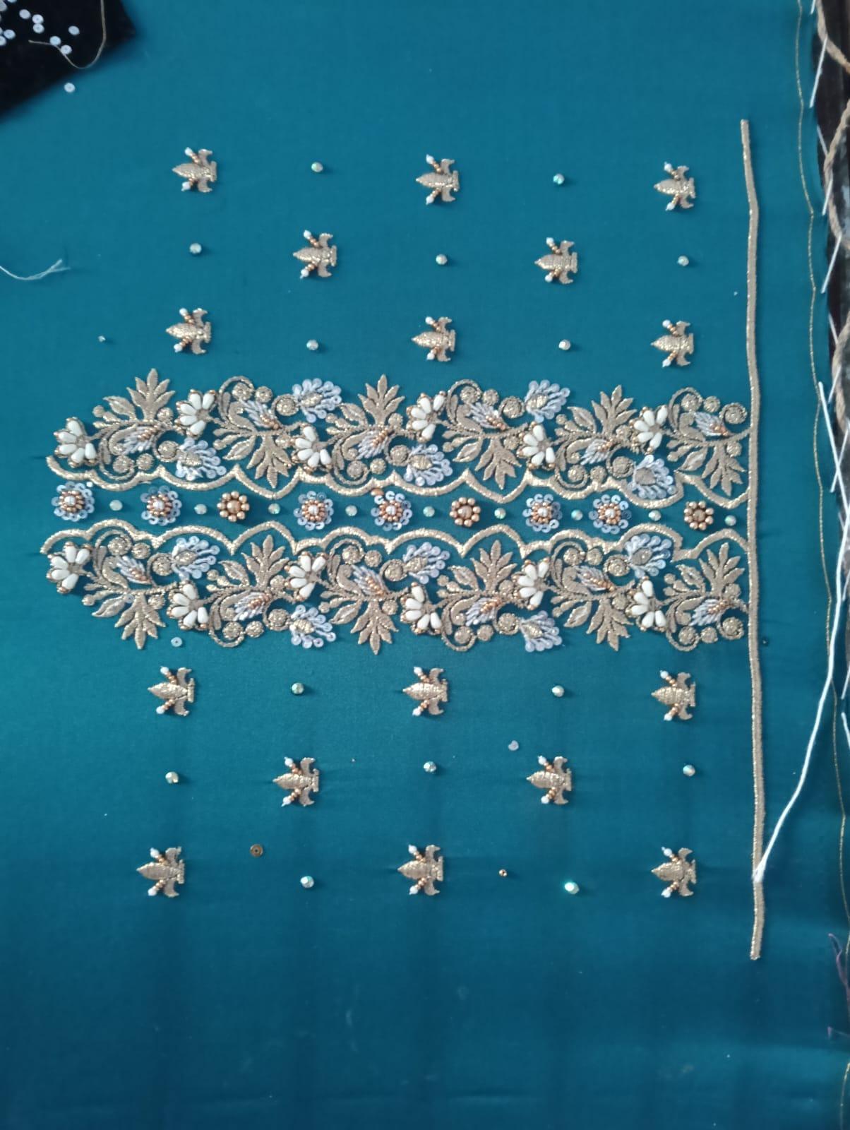 Teal fabric with ornate zari embroidery and scattered beadwork border