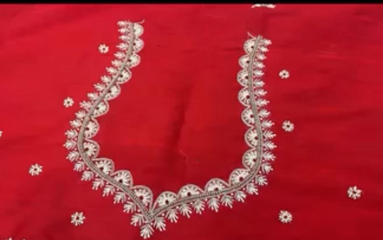 Red bridal blouse with intricate white zari embroidery neckline