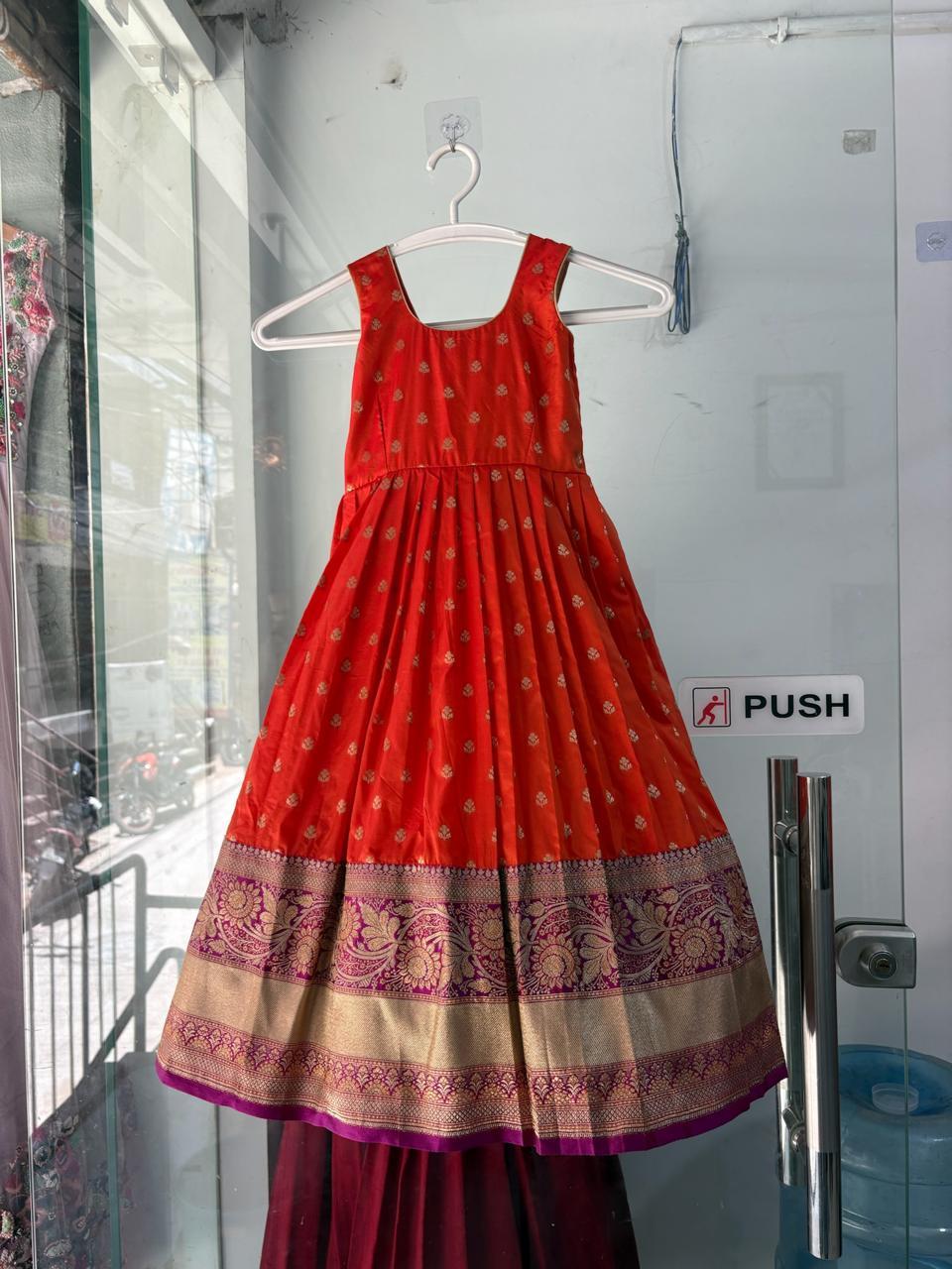 Red silk half saree with gold brocade border and ornamental hem