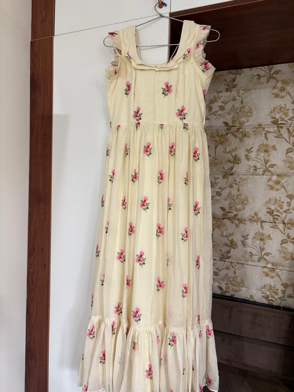 Cream sleeveless gown with scattered pink floral embroidery and ruffled hem