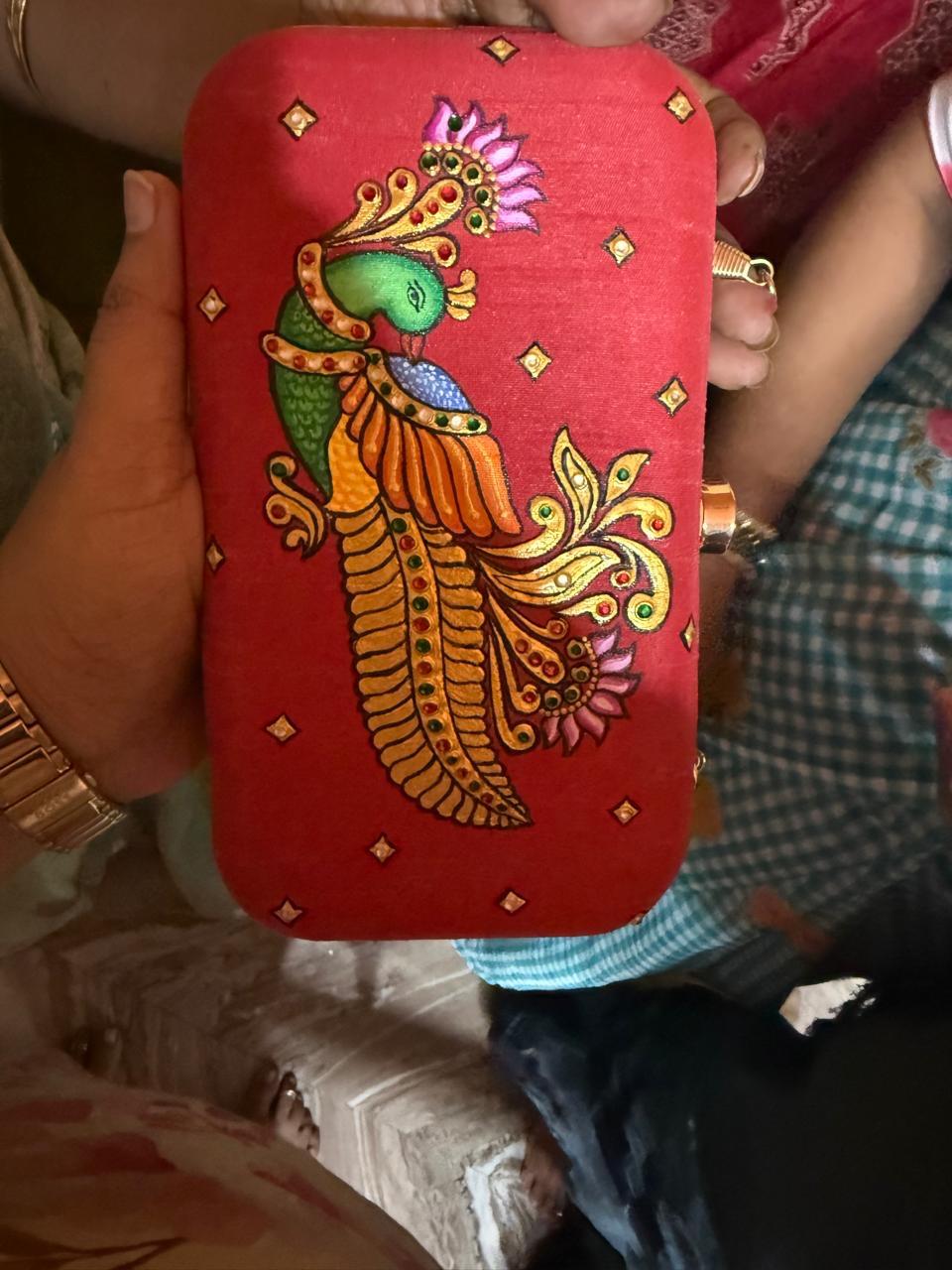 Red clutch with ornate peacock design and gold embroidery details