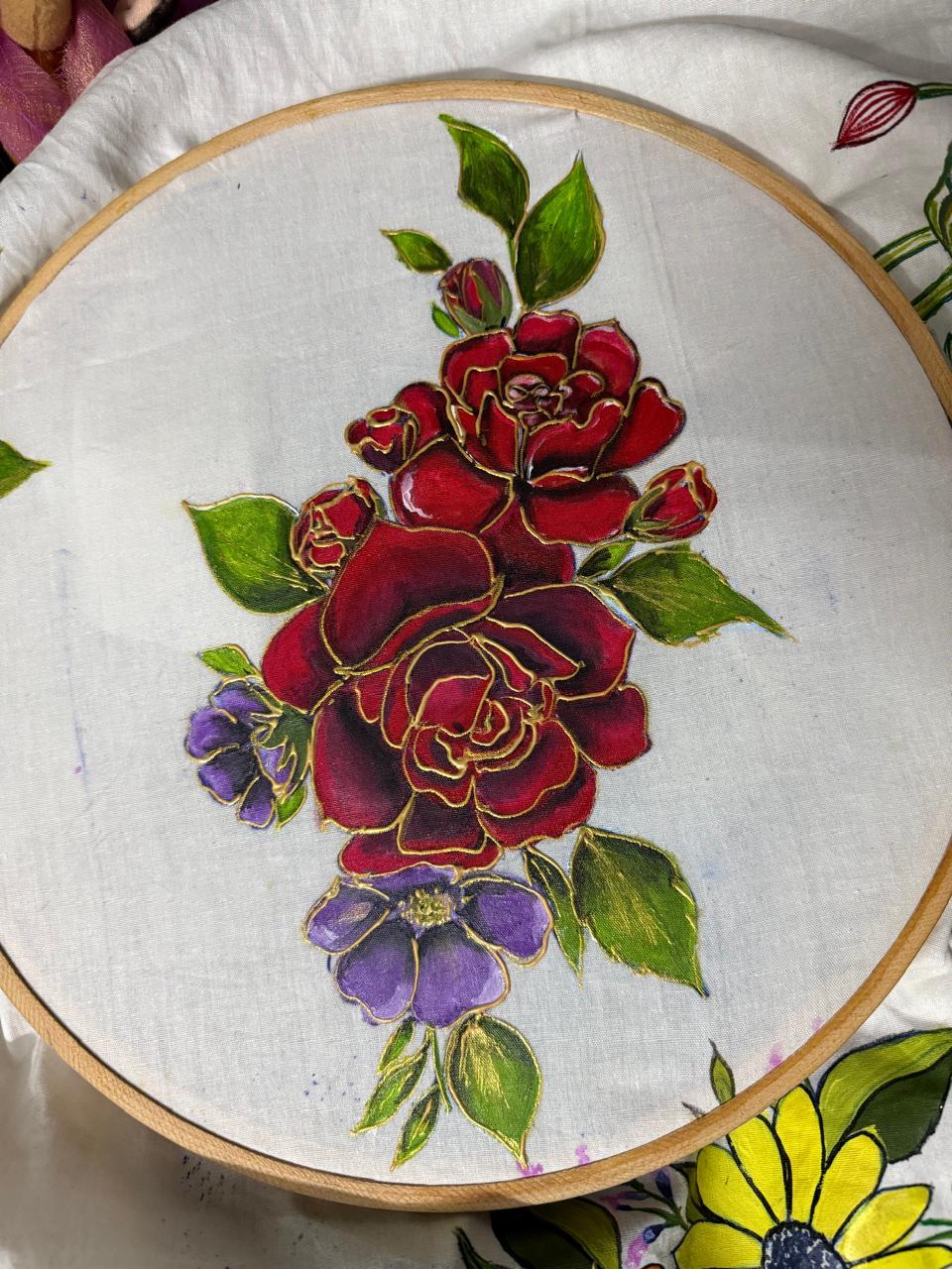 Hand-embroidered floral hoop art with red roses and purple flowers