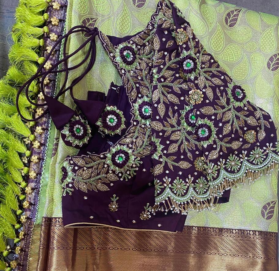 Elegant dark purple bridal blouse featuring intricate maggam work, green stone embellishments, and handcrafted tassel detailing for weddings and festive occasions.