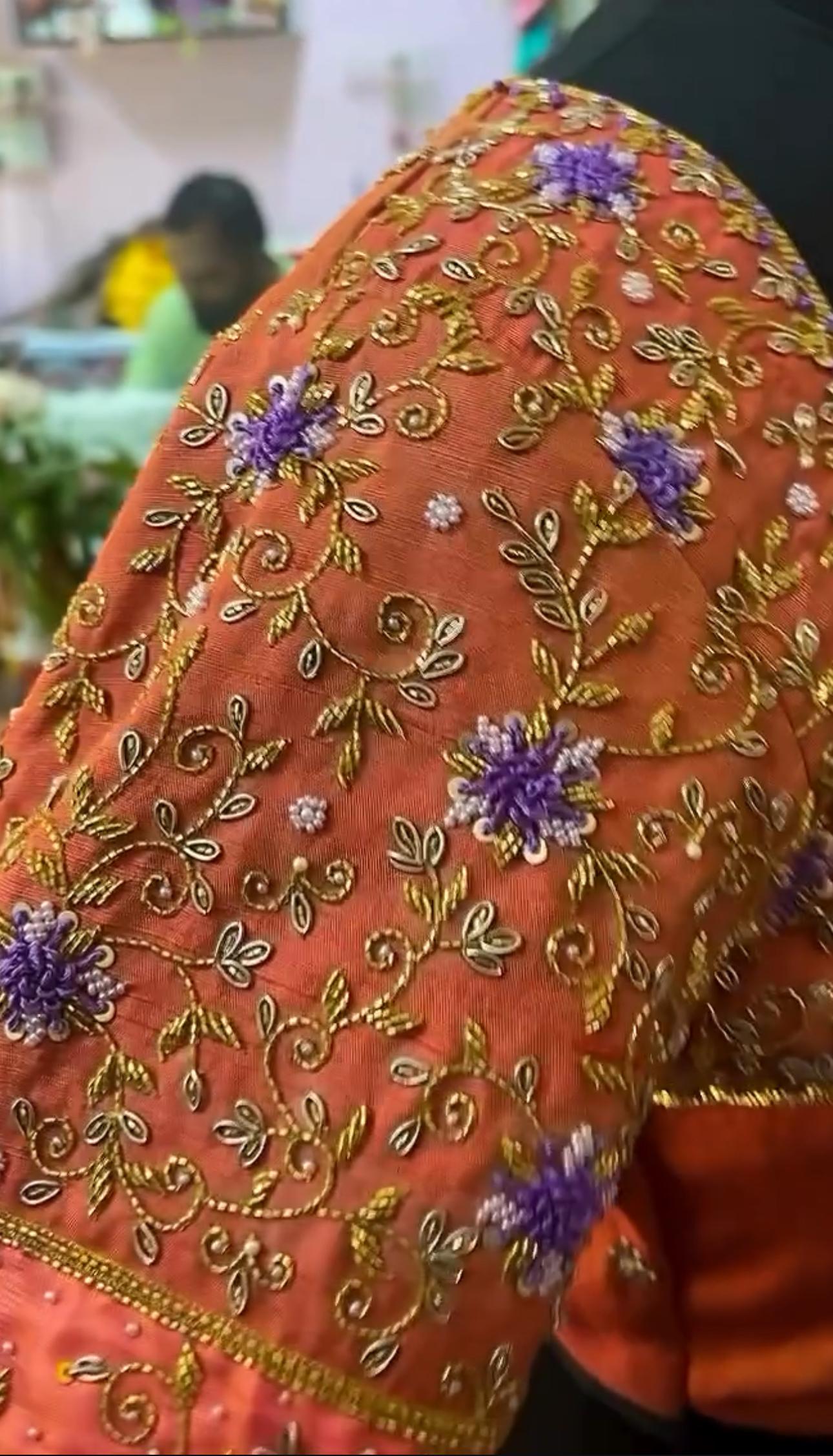 Orange blouse sleeve with colorful floral maggam work embroidery