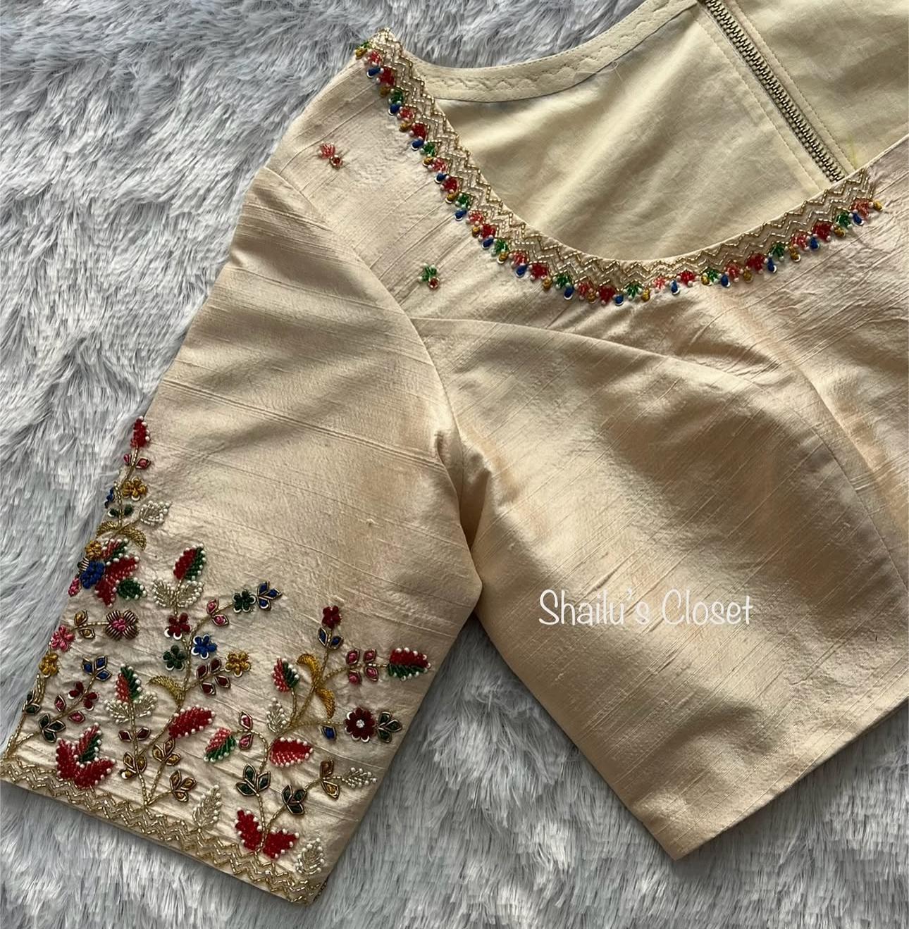 Cream blouse featuring delicate floral embroidery on sleeves and neckline, perfect for elegant festive wear.