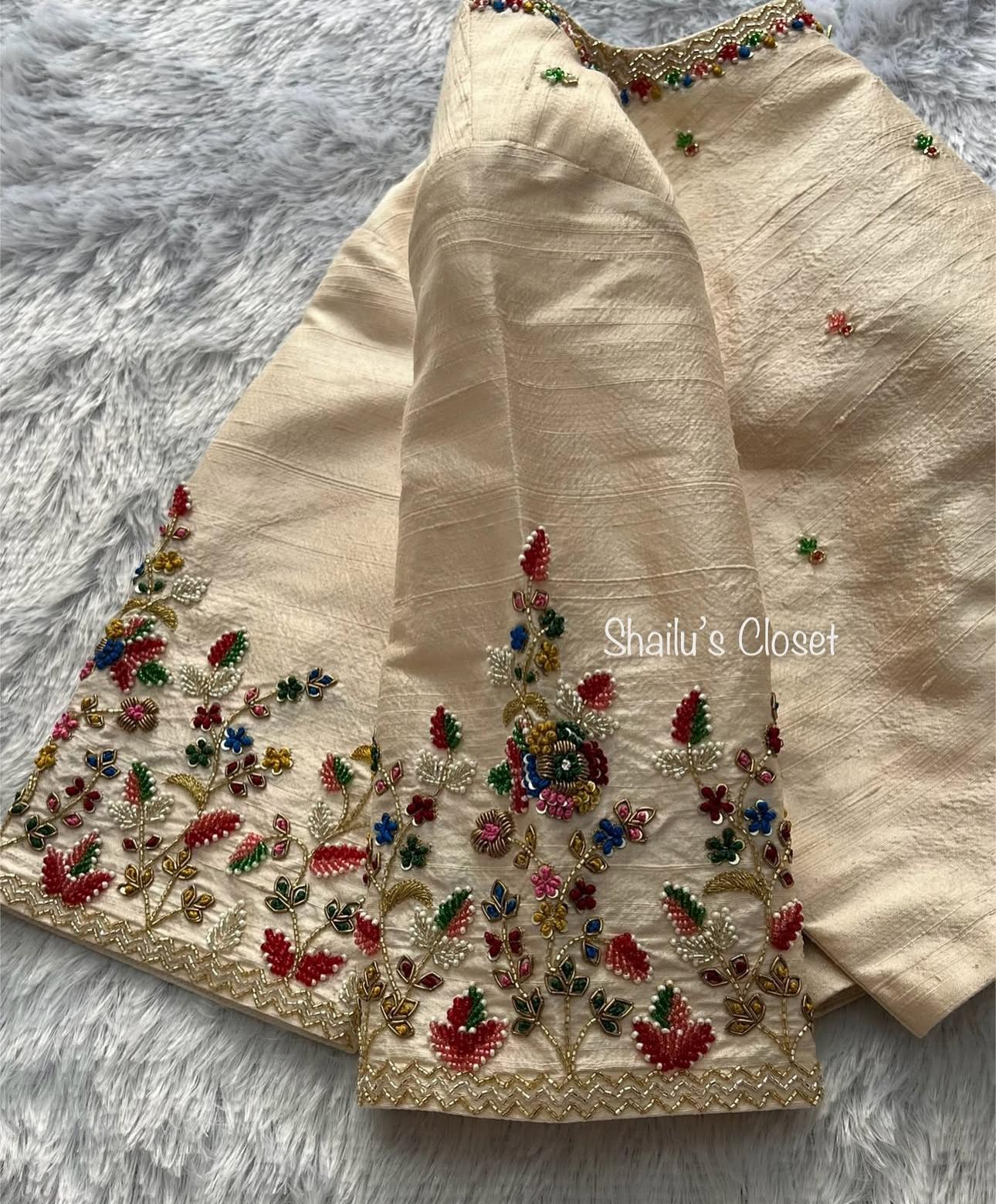 Cream designer blouse with dense floral embroidery along sleeves and neckline, ideal for wedding sarees.