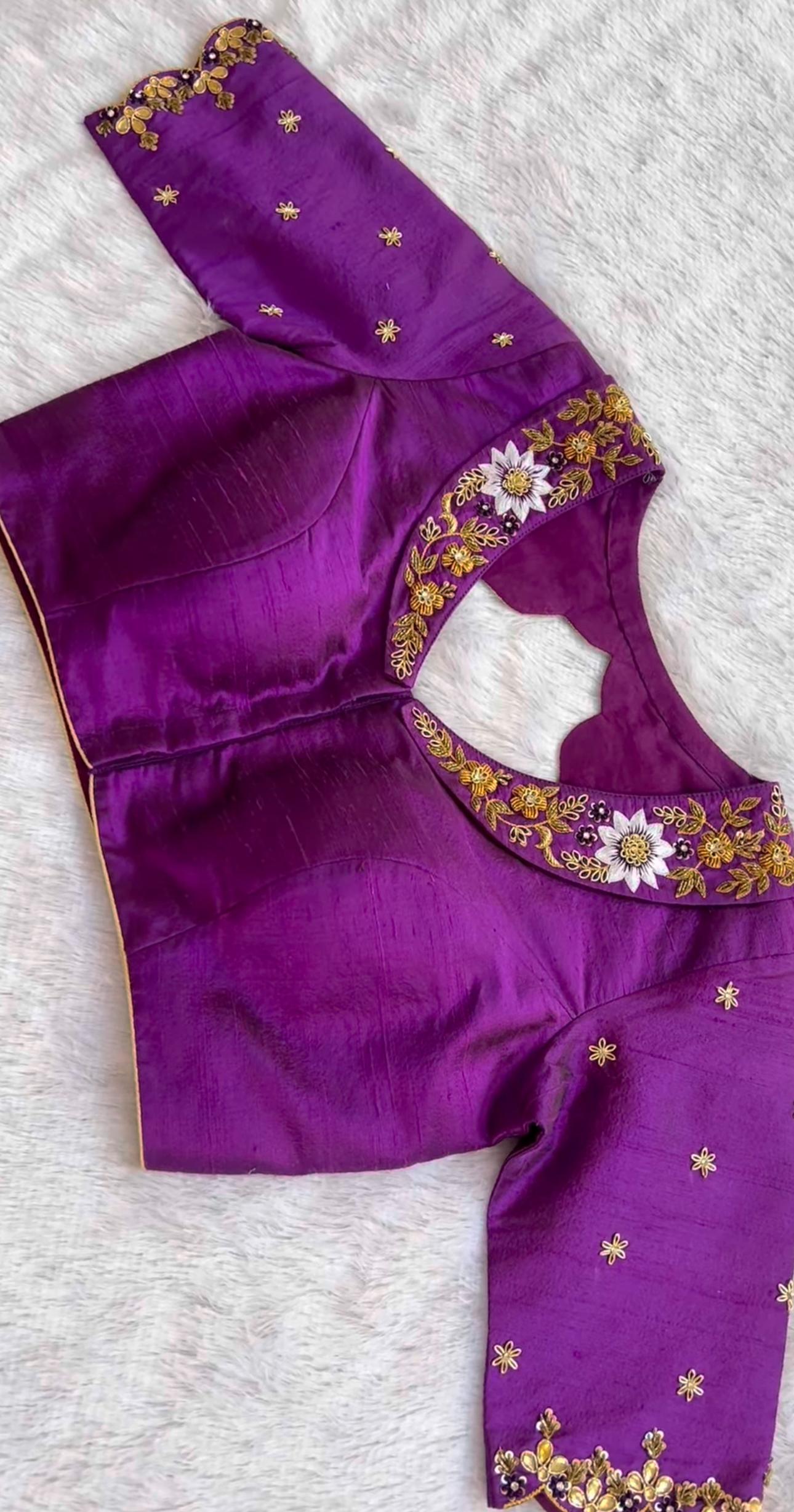 Rich purple blouse featuring floral maggam embroidery around the neckline, ideal for festive occasions and elegant saree looks.