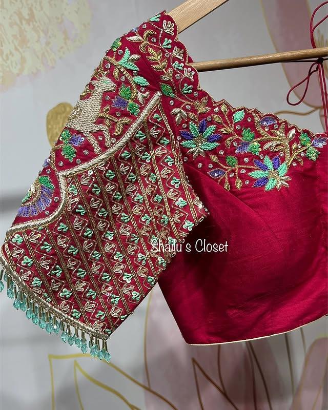Rich red bridal blouse with heavy maggam embroidery and intricate stone detailing, ideal for grand wedding and reception outfits.